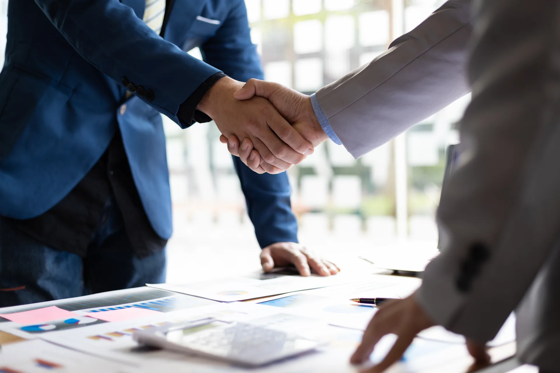 Two people shaking hands across a table after settling terms