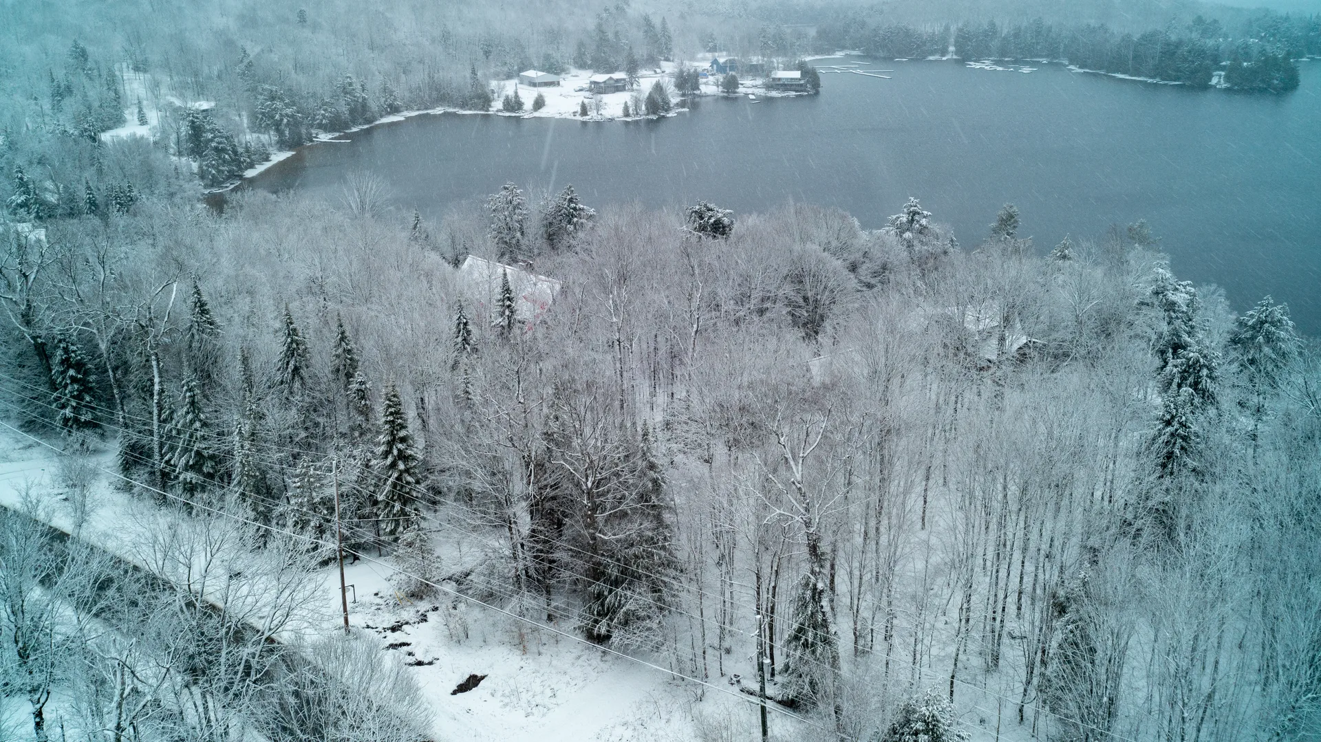 Aerial view of waterfront cottages on a frozen lake in winter, the off-season face of a four-season market