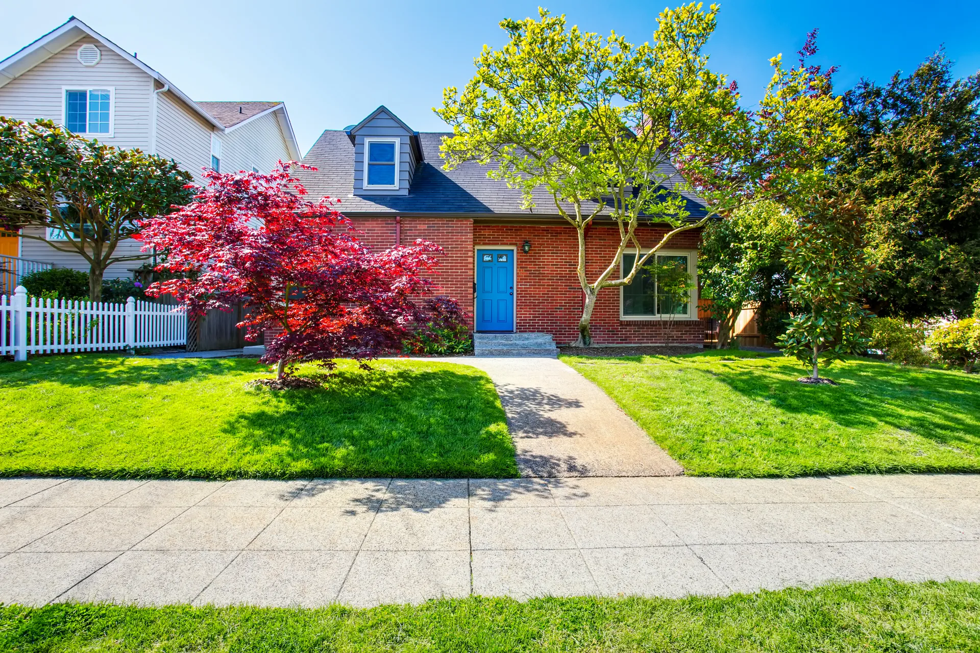A red-brick century home with a deep front porch, the kind of stock that anchors older Ontario cores