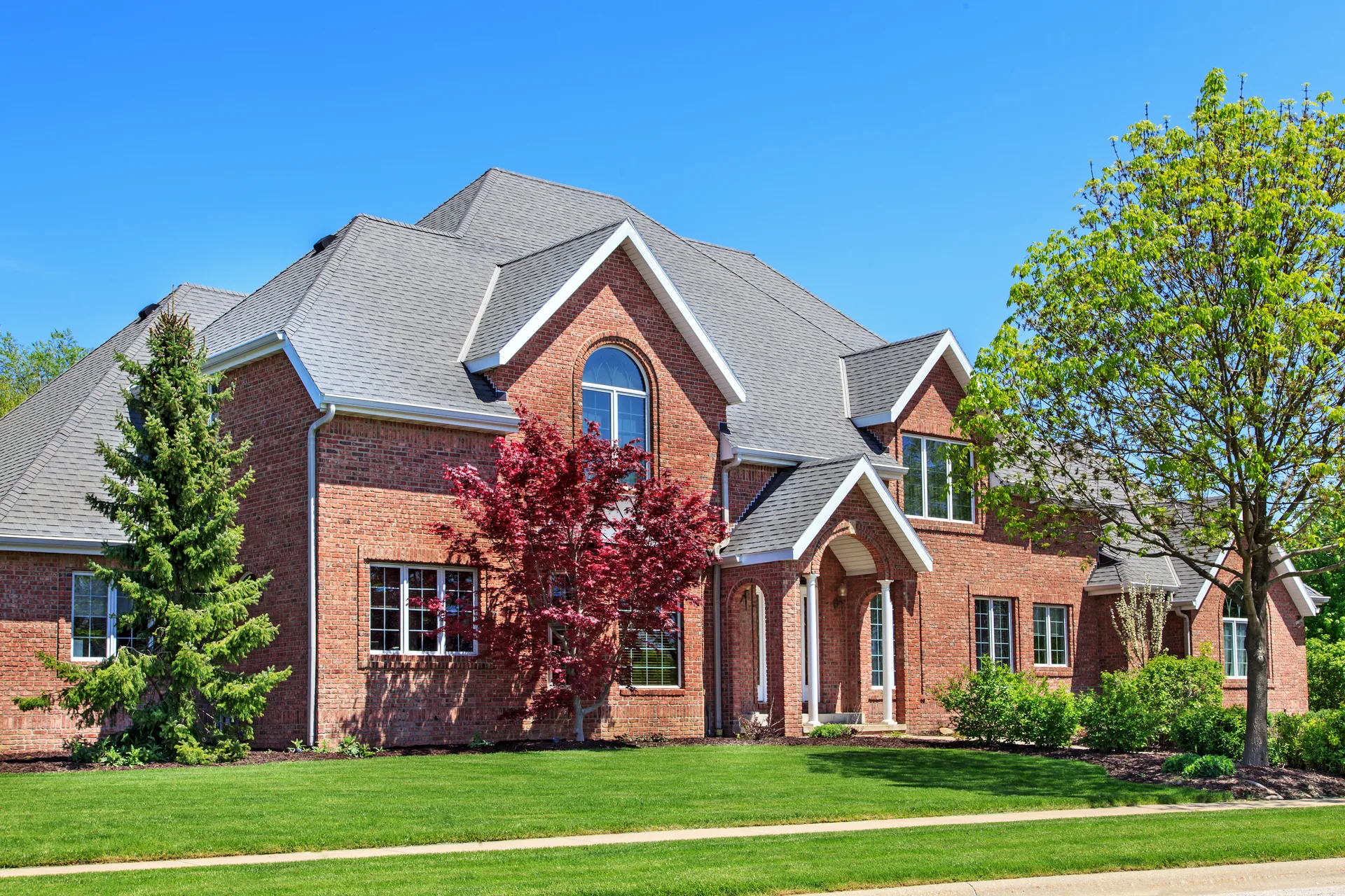 A stately red-brick home behind mature landscaping, the calibre of property a heritage luxury market trades in