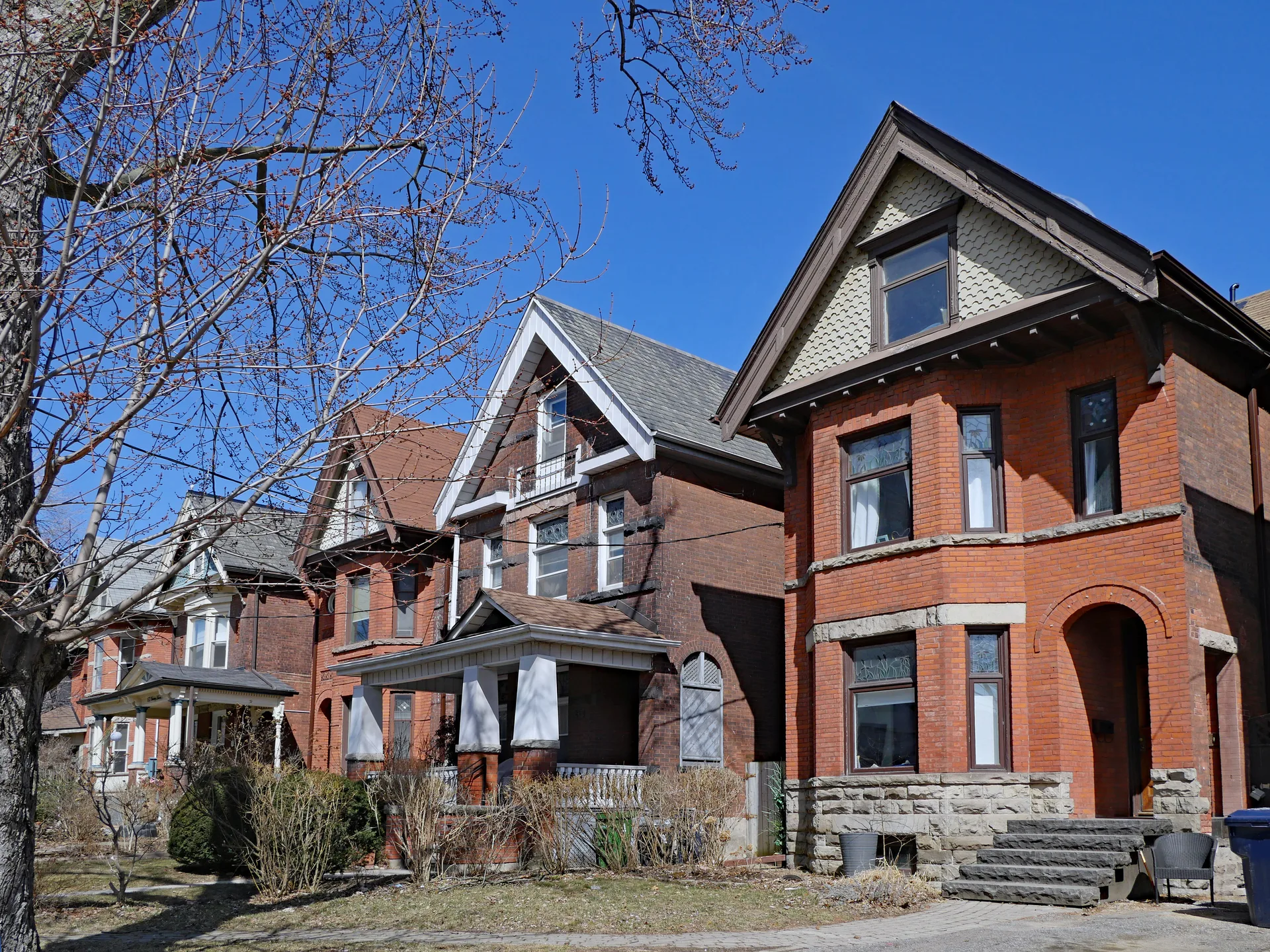 A row of historic brick homes on a mature street, the heritage stock that defines an old Ontario downtown