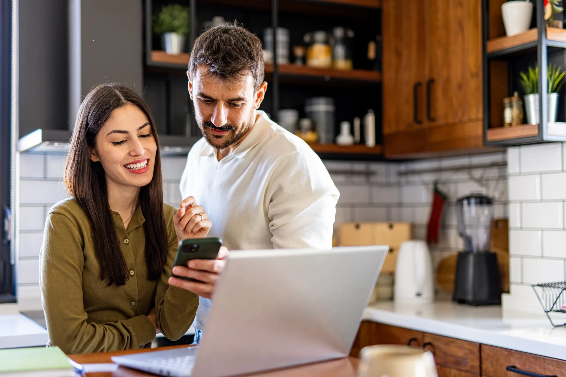 A couple reviewing new listing matches together at the kitchen counter