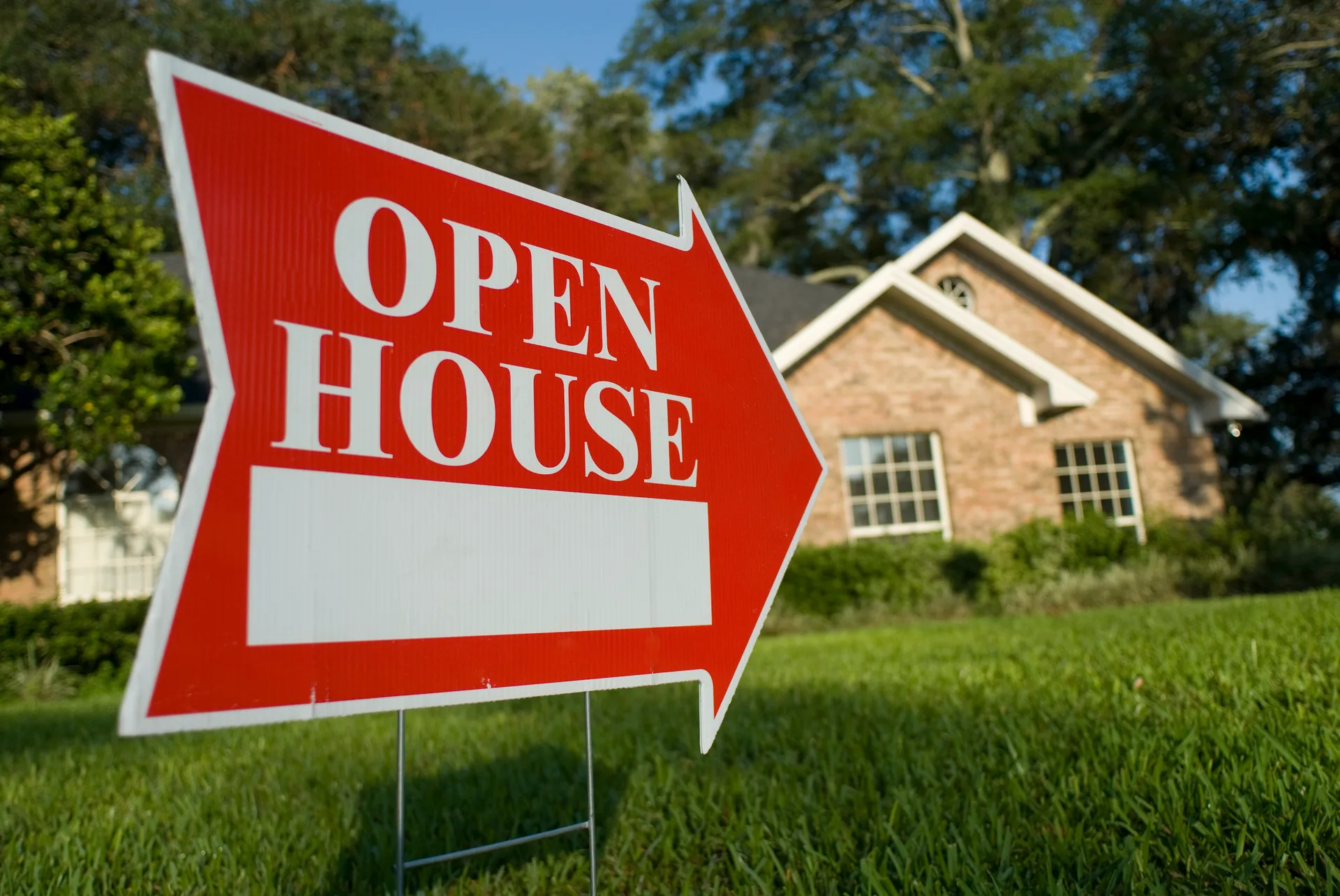 An open-house sign in front of a brick home — signage is where an address-style URL earns its keep